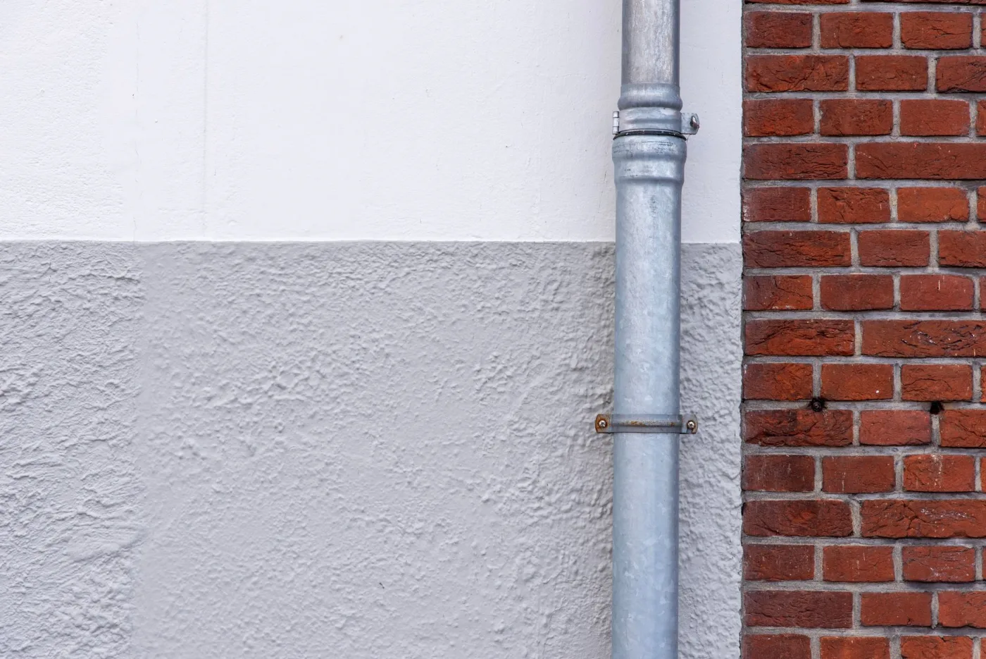 Exterior drain pipe running down a painted brick wall