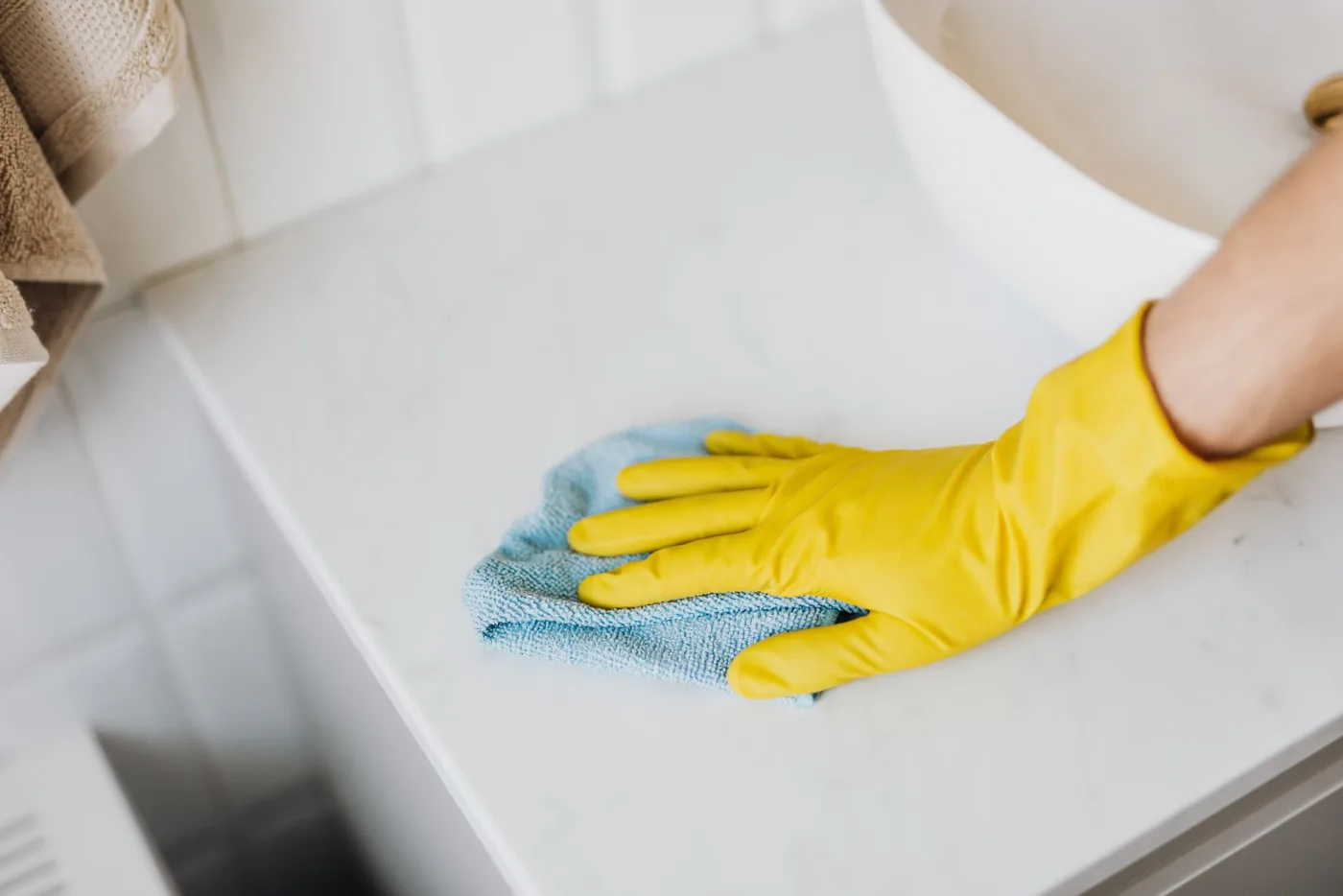 A gloved hand wiping a clean kitchen counter until it shines