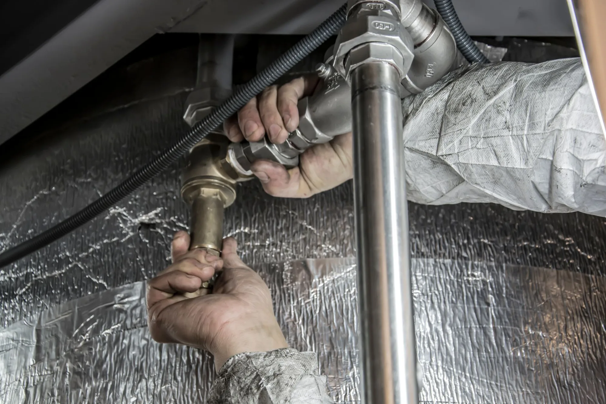 Uniformed plumbing technician kneeling beside an Atlanta home checking pressure gauges