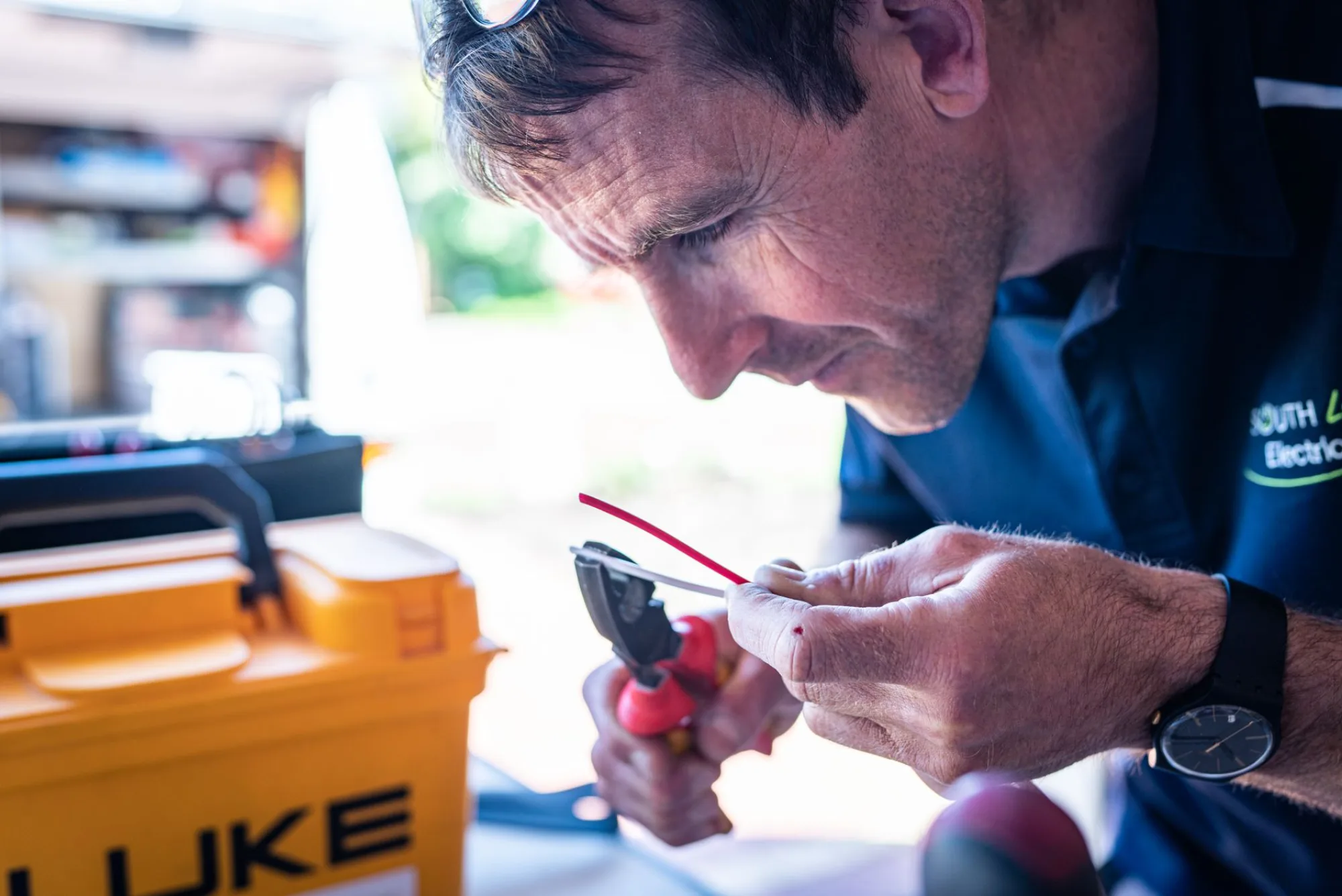 CBX electrician testing a circuit with hand tools on a job site