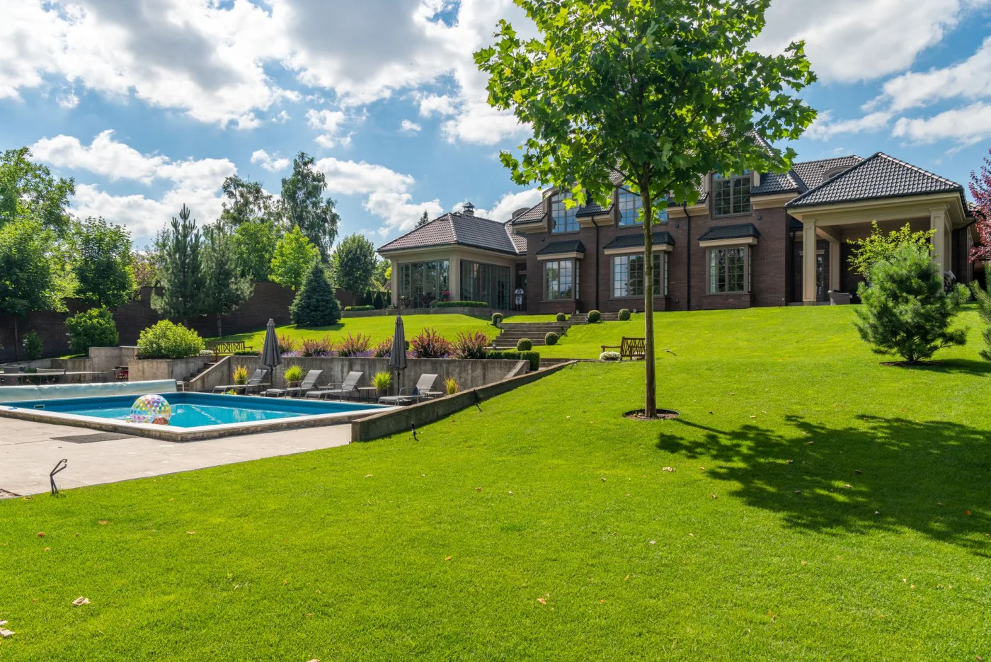 A manicured lawn and tidy landscaping beside a home with a pool