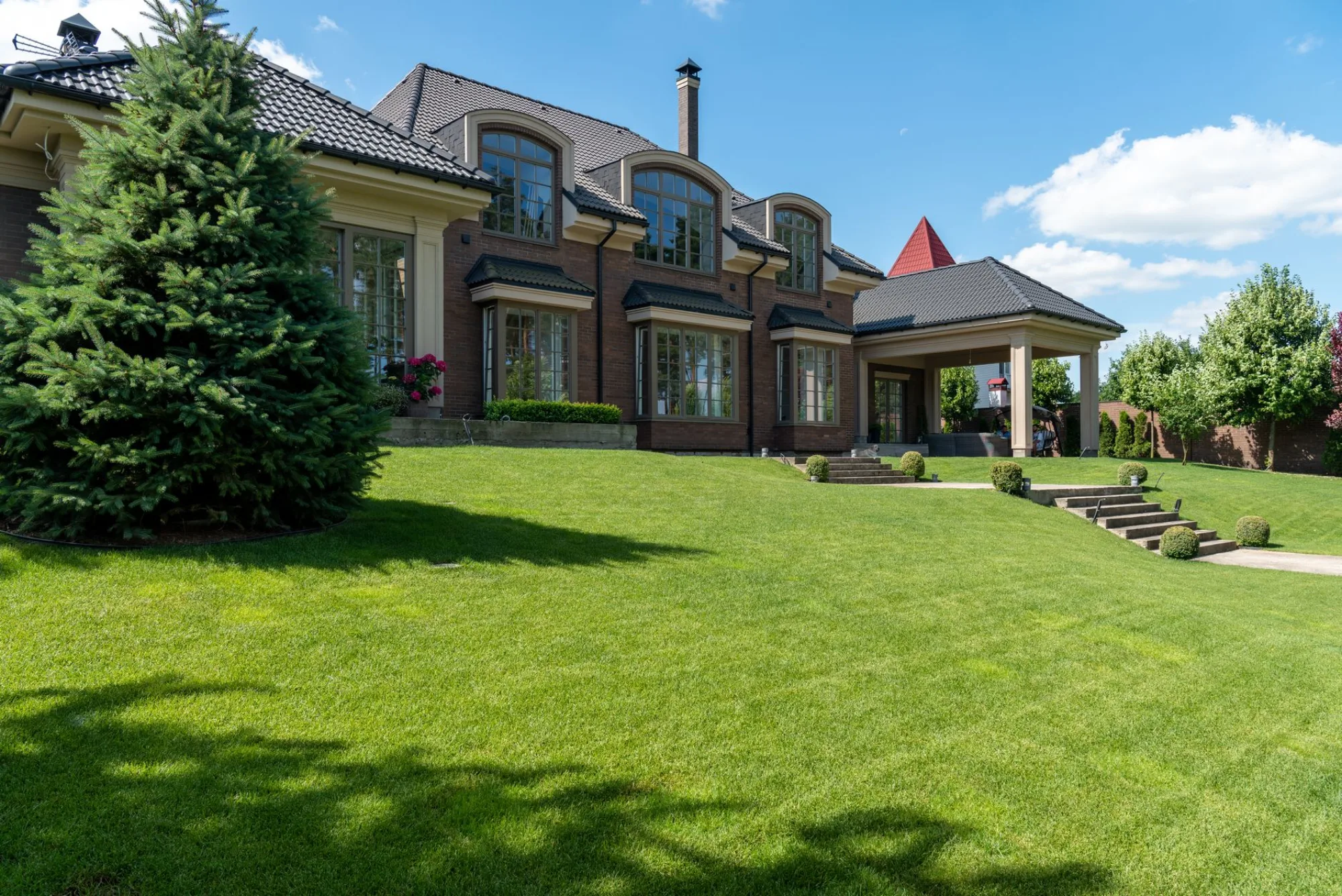 A lush, freshly mowed green lawn in front of a traditional home on a sunny day