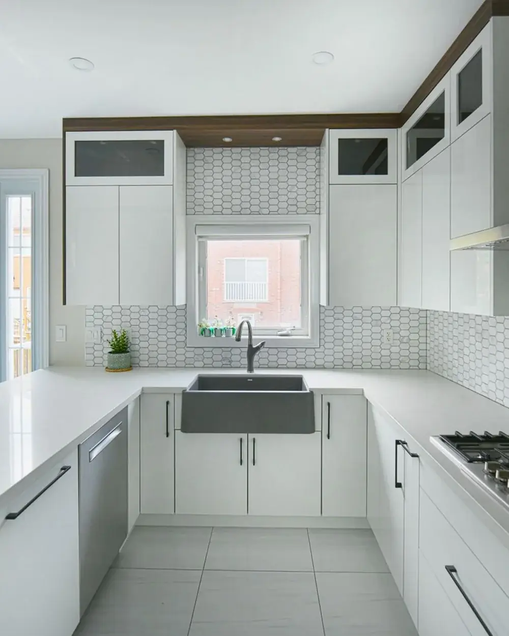 A kitchen with a herringbone tile backsplash and a stainless steel range hood above the cooktop