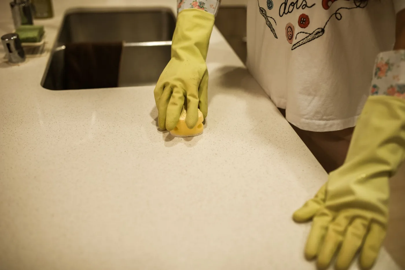 A gloved hand carefully wiping down a kitchen counter