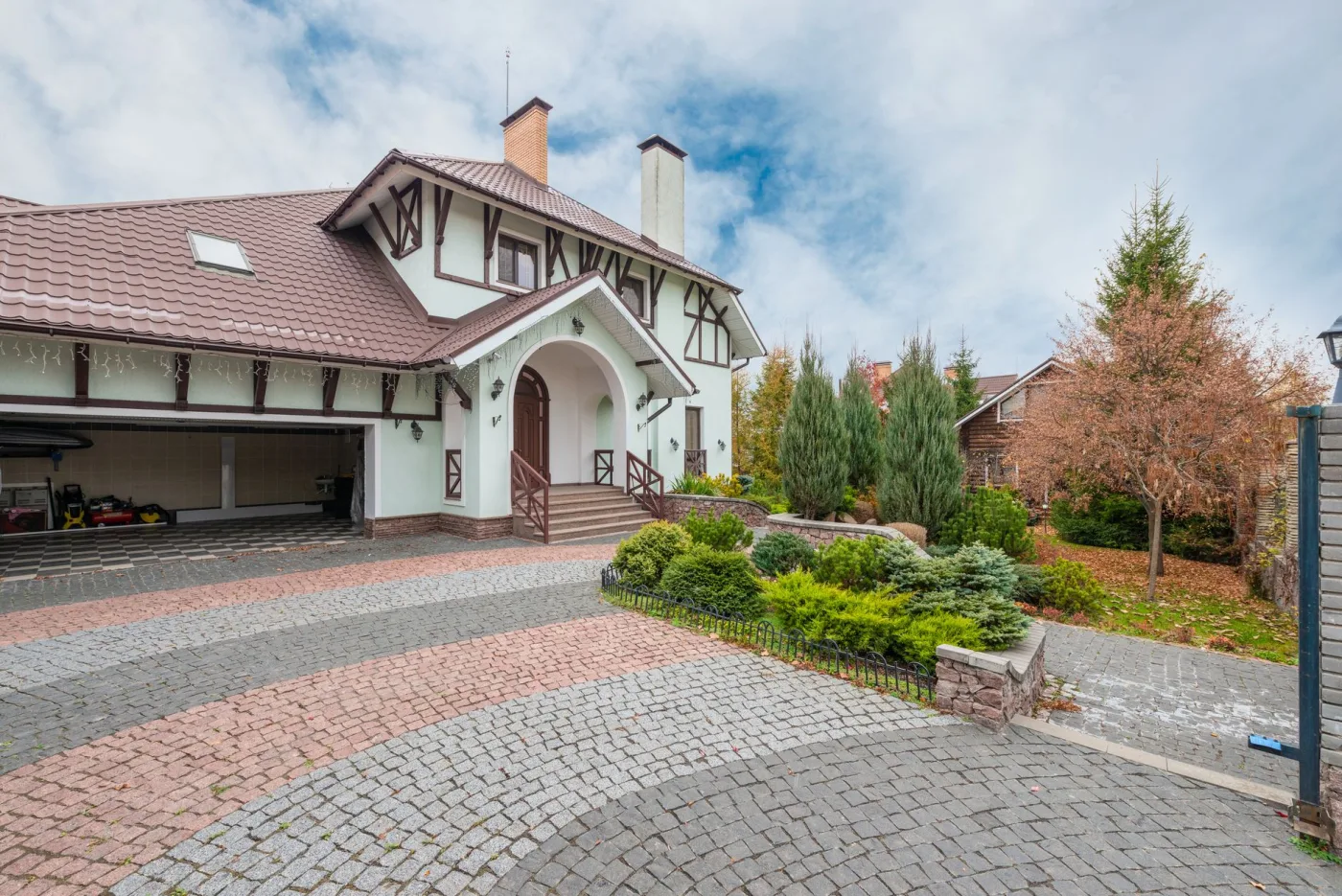 A large home with a freshly cleaned brick and cobblestone paver driveway