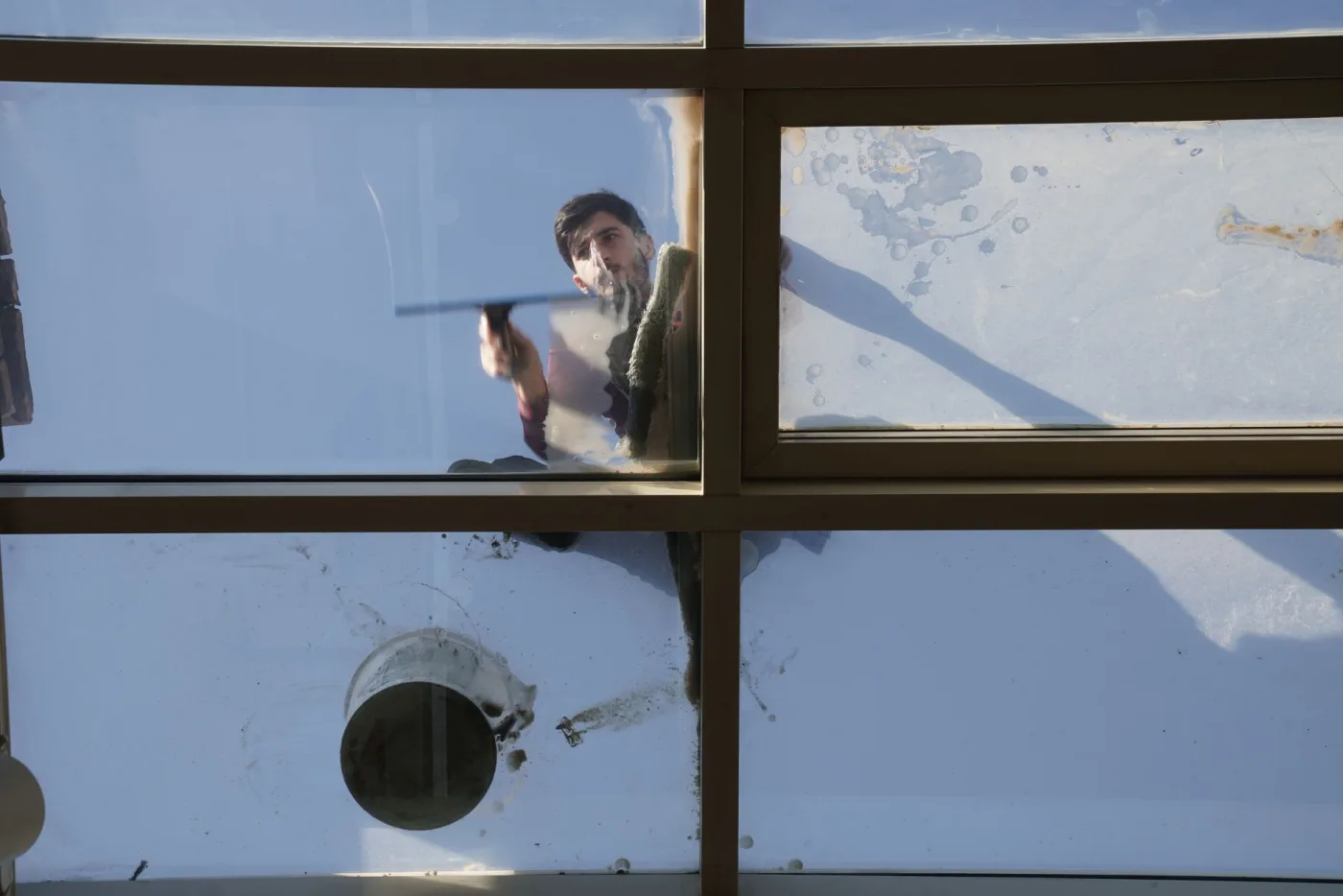 A technician detailing a large glass panel to a clean, streak-free finish