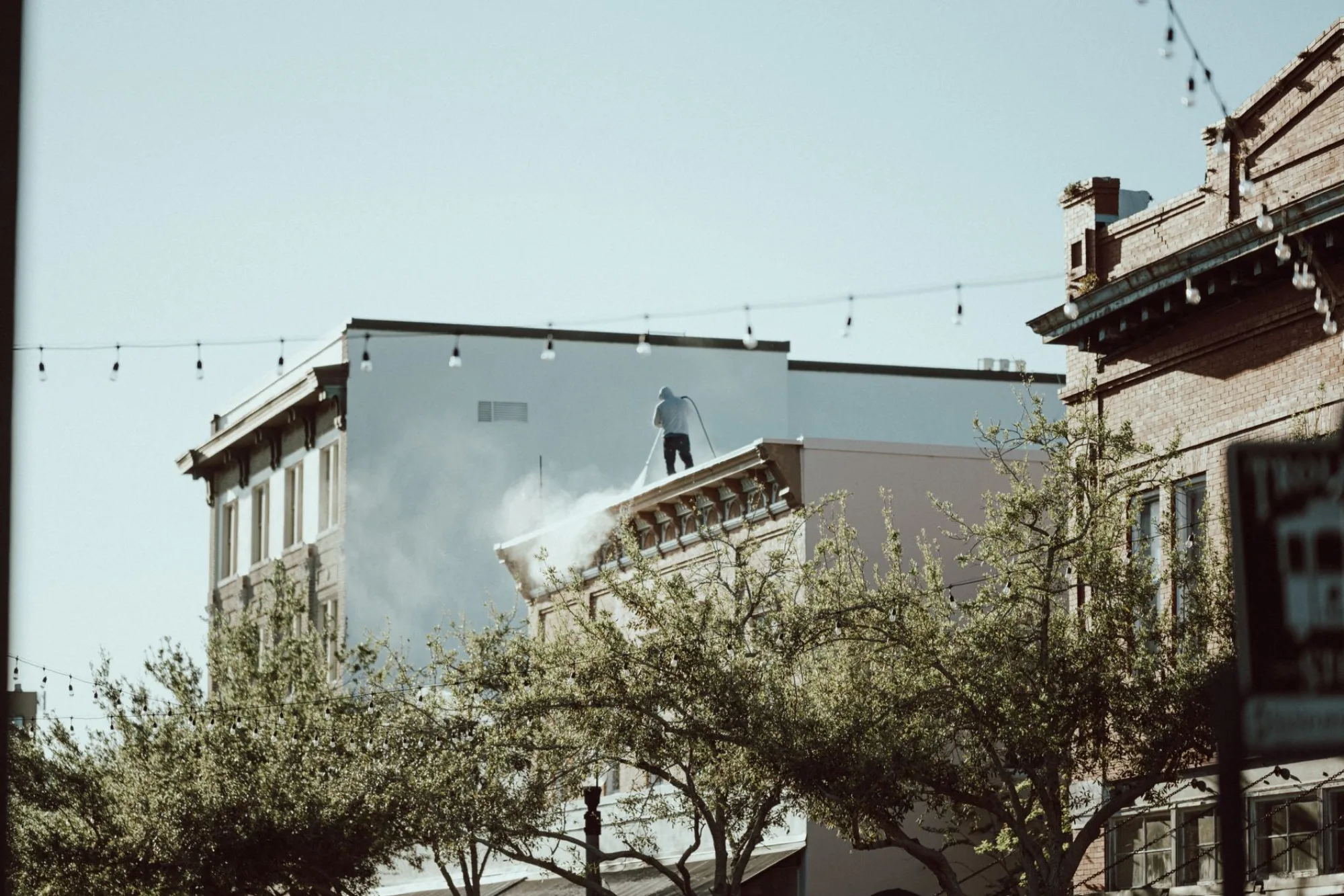 A technician soft-washing the exterior of a building in metro Atlanta with a wide spray of water