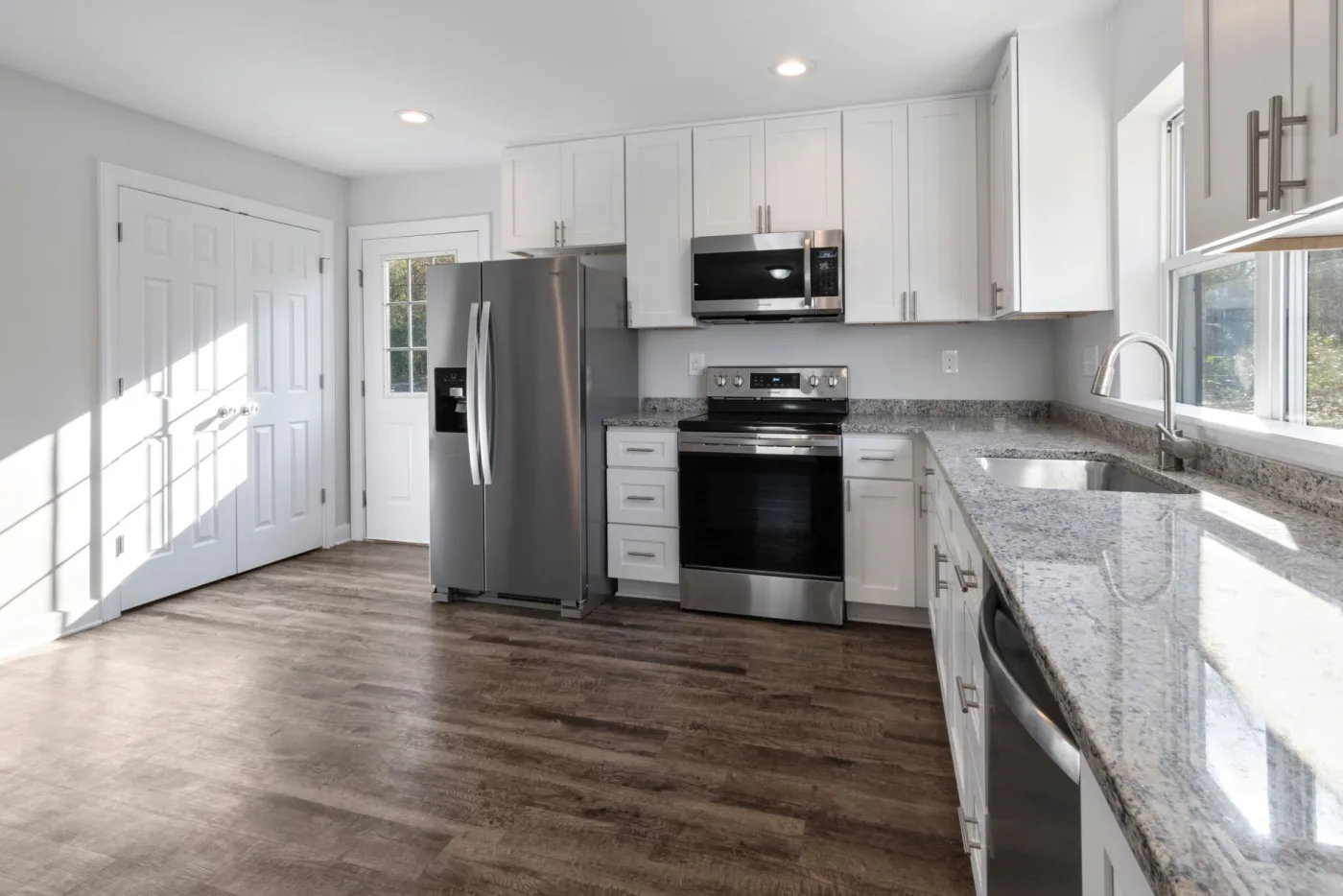 Finished kitchen remodel with white shaker cabinets, granite counters, and stainless steel appliances