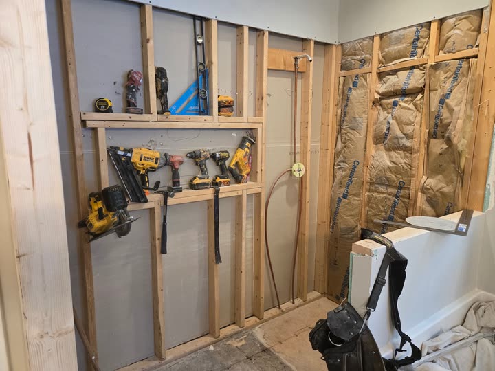 The wet wall framed and insulated, with the tools laid out along the plate.