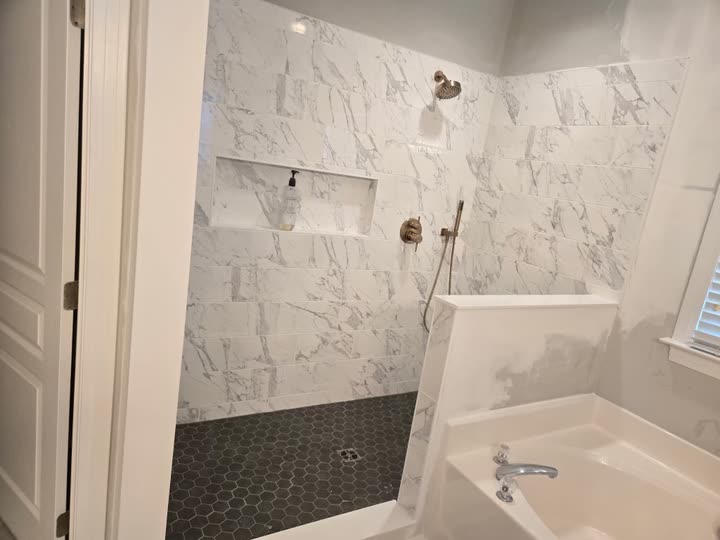 The tiled shower seen from the doorway, with the garden tub in the foreground.