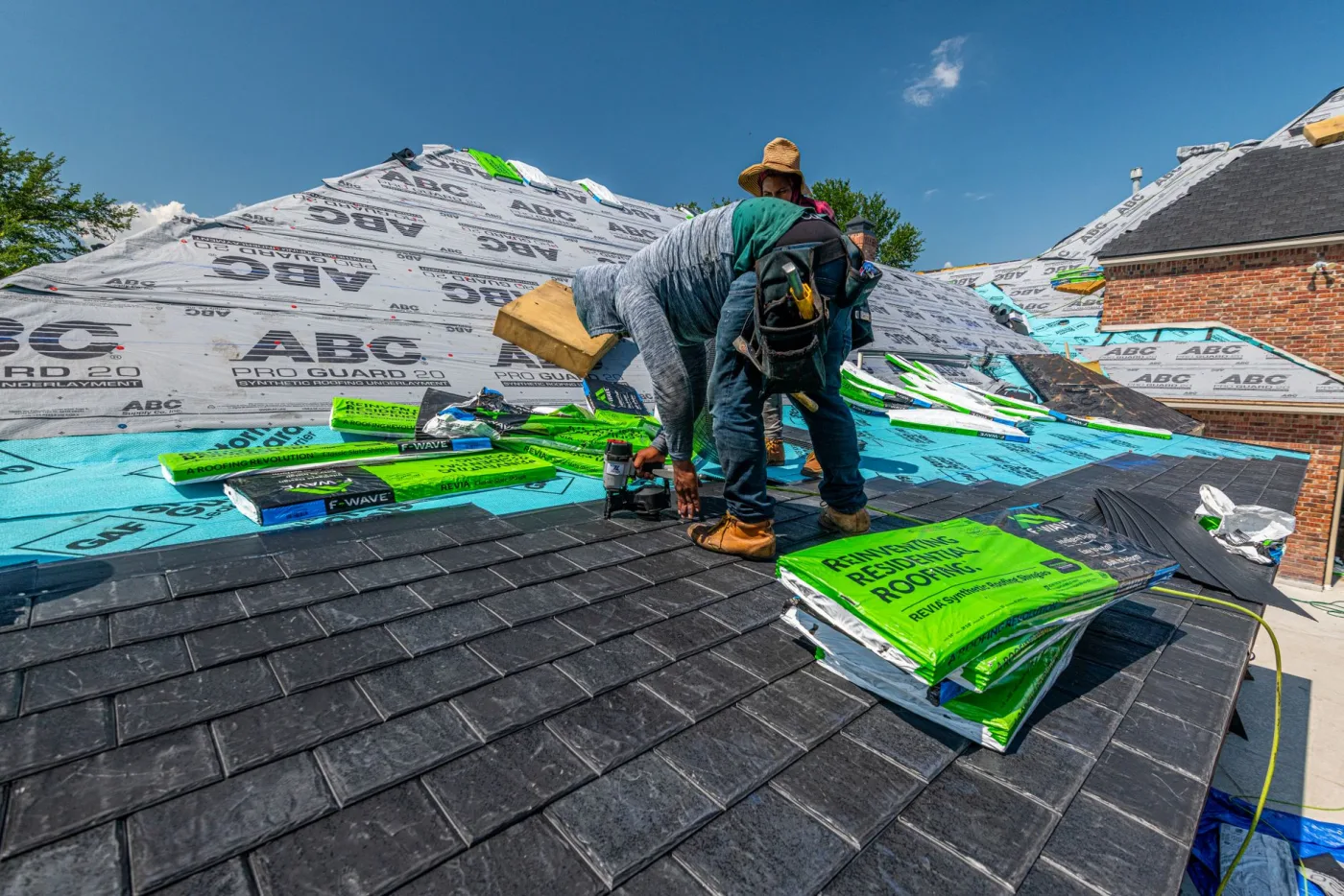 A roofer laying a fresh course of asphalt shingles