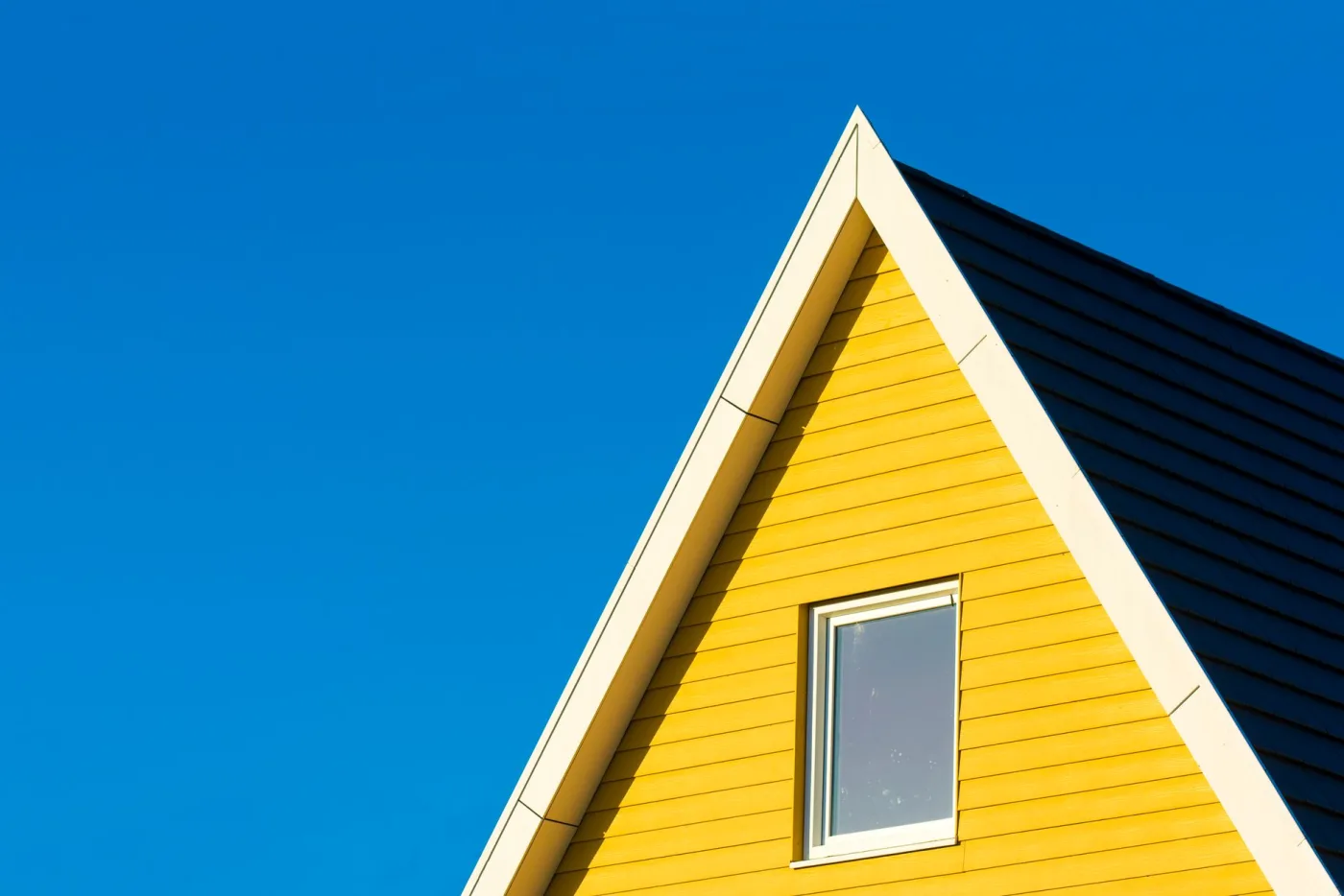 Sharp gable end with clean horizontal siding and white rake trim against a blue sky