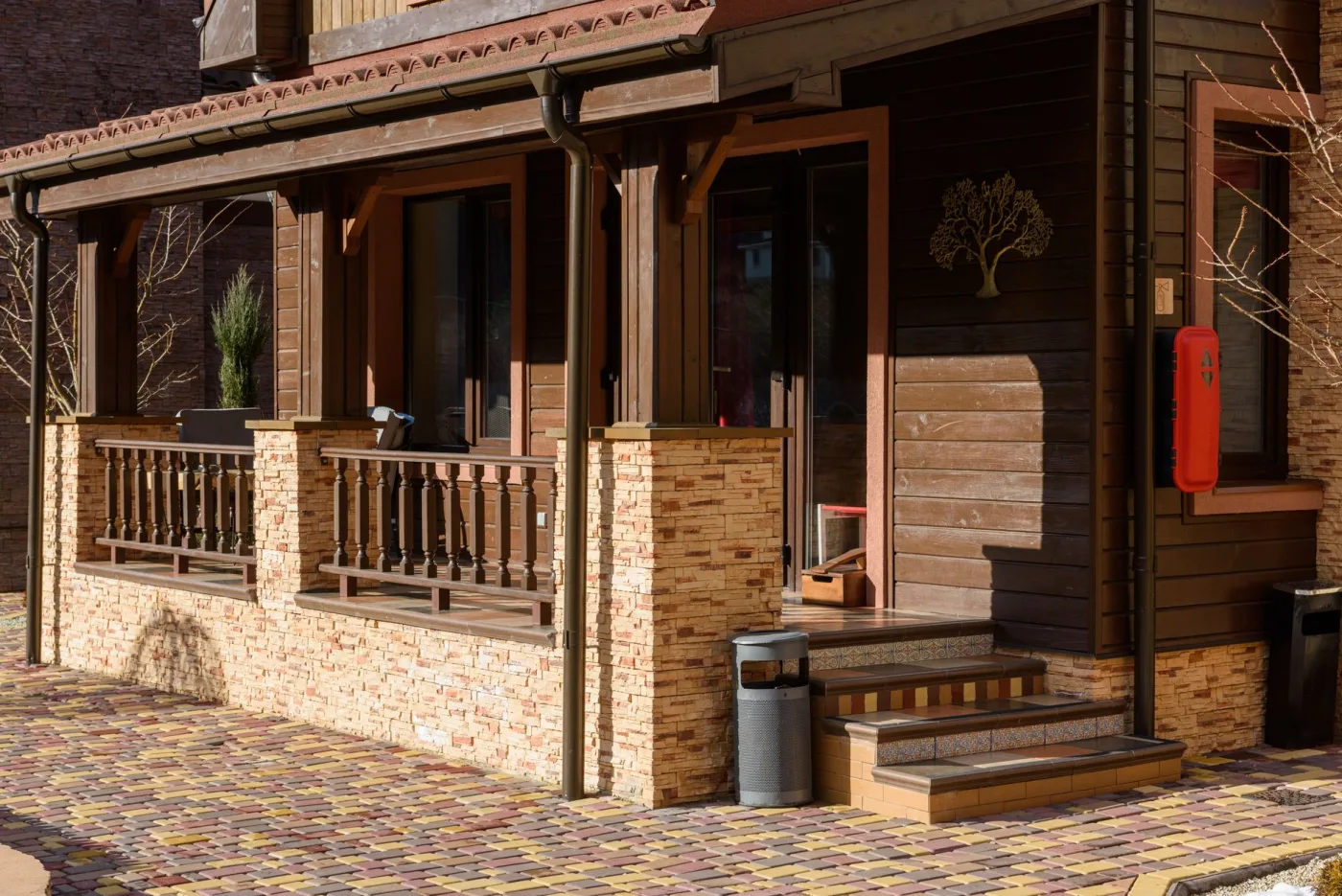 Covered porch with wood cladding, stone column bases, and tiled steps